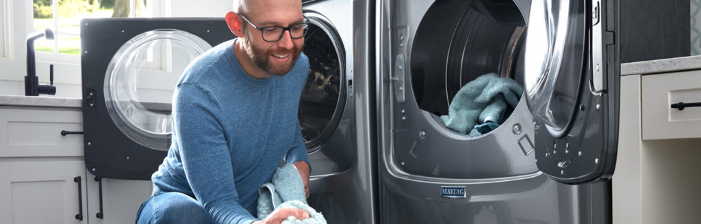 man loading washing machine with blue towels