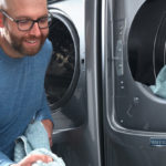 man loading washing machine with blue towels